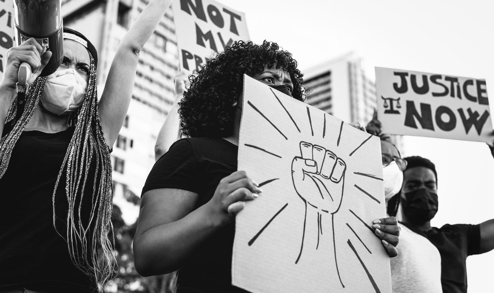 Photo of protestors holding signs showing their opposition to racism and police brutality.