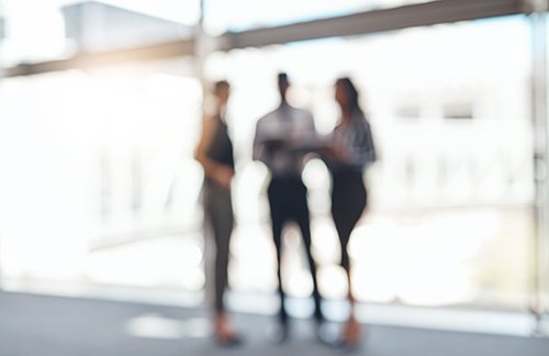 Out of focus photo of three people standing and talking