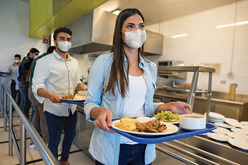 Photo of students wearing masks in line at a school cafeteria.