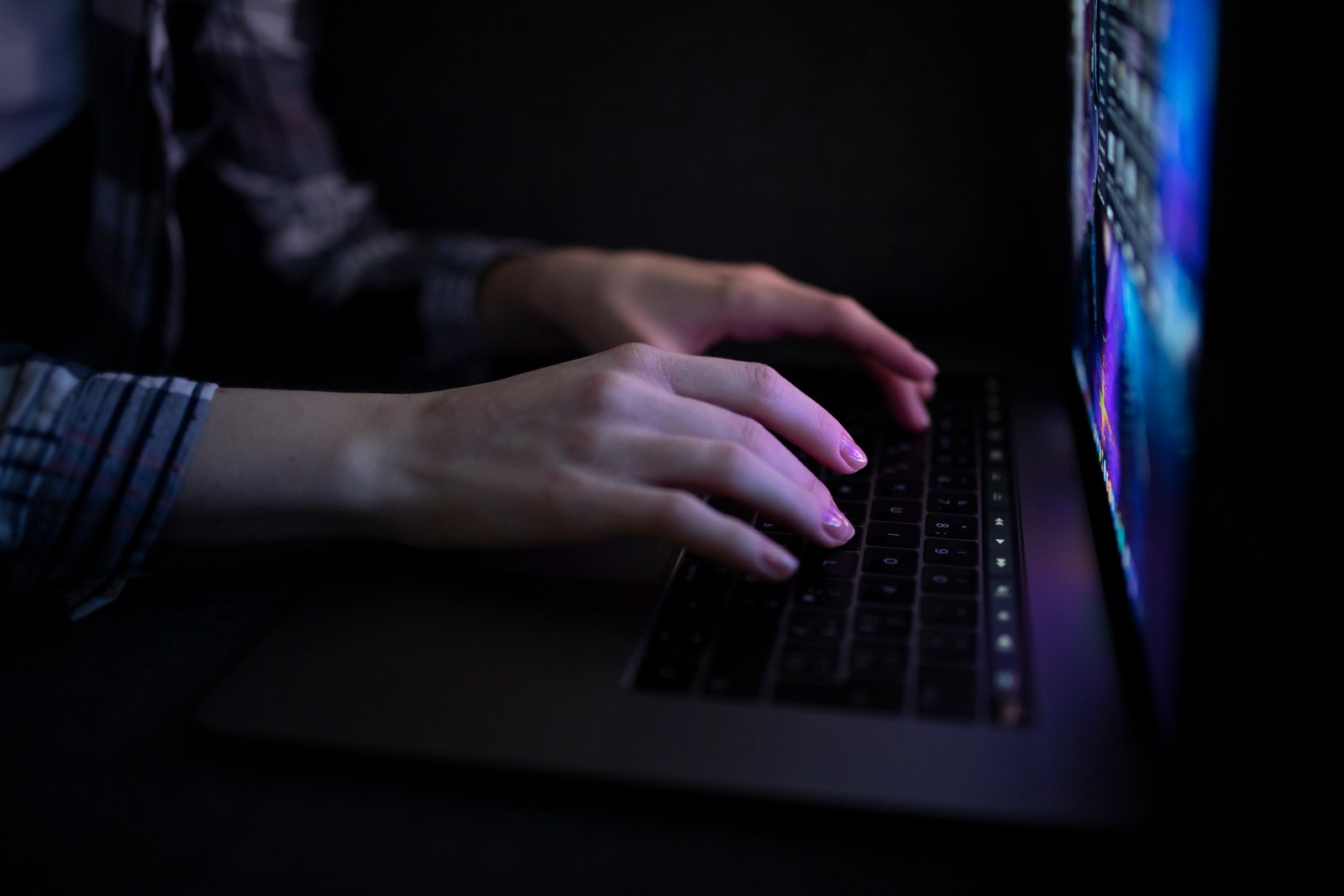A woman's hands typing on a laptop