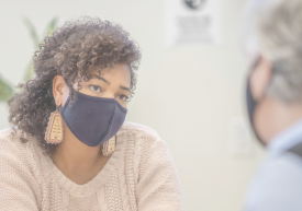 Photo of two people facing each other while wearing facial masks.