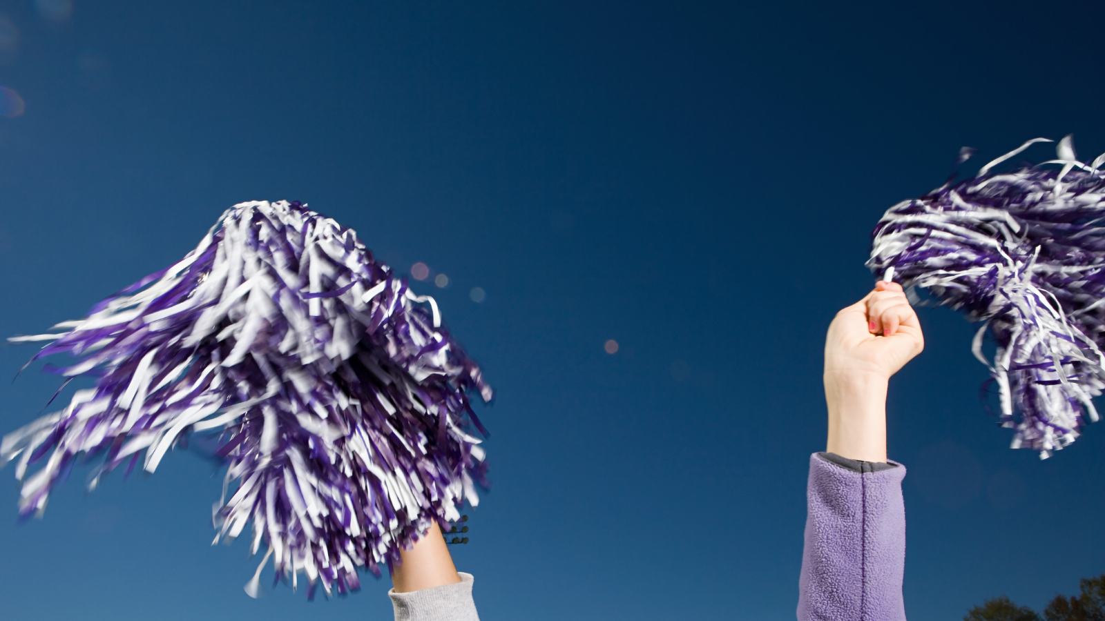 Photo of a cheerleader's hands holding pom poms.