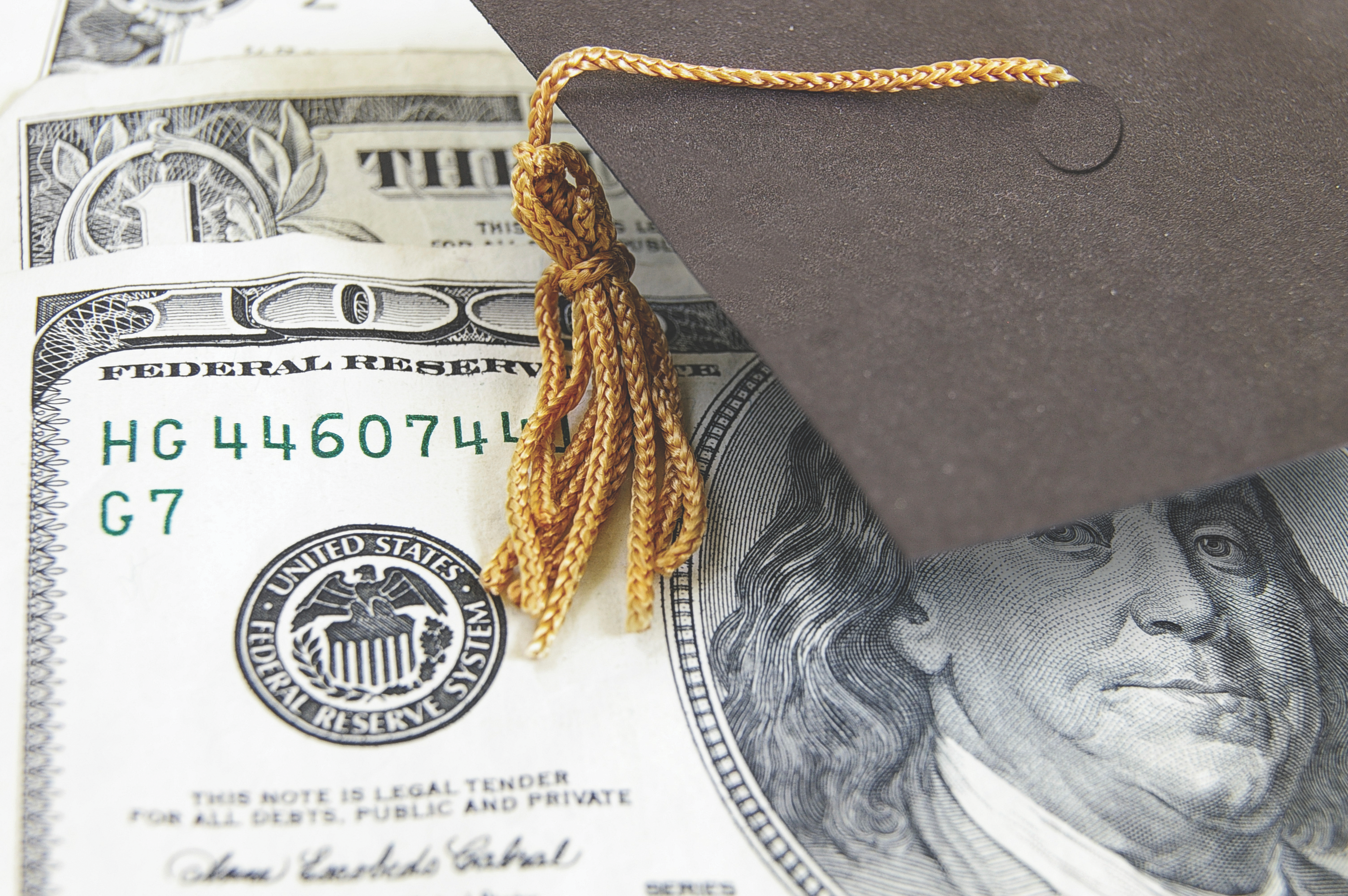 Photo of a mortarboard hat placed on top of a U.S. one hundred dollar bill