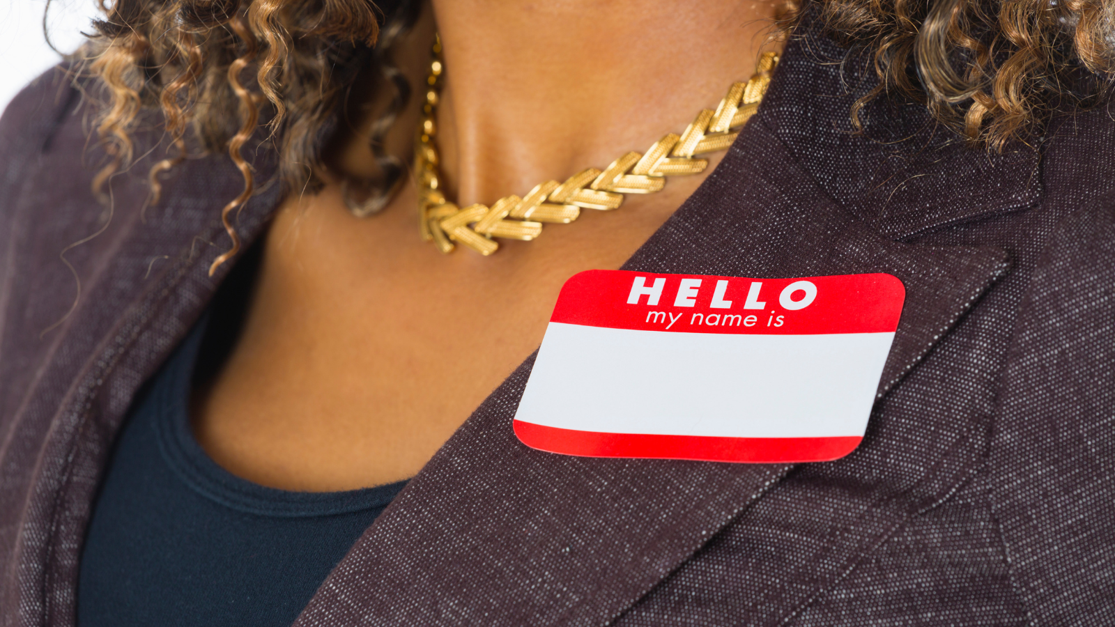 Photo of a woman picture from the neck down wearing a nametag to emphasize the importance of accurate name pronunciation.