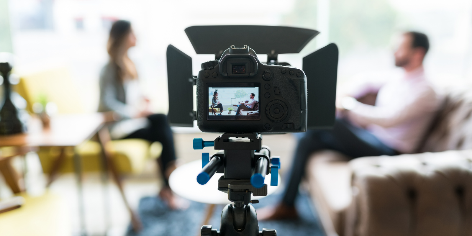 A video camera is filming two people having an interview in the background